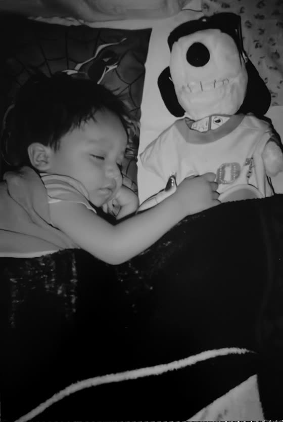A baby asleep hugging a Snoopy plush