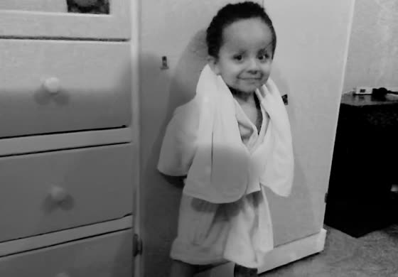 A young child wrapped in a towel after a bath, smiling